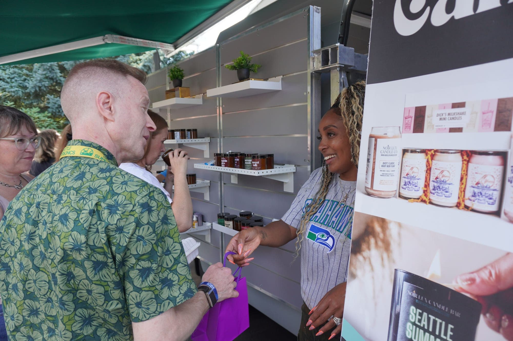 Colina handing a purple gift bag to a customer at the open side of the van