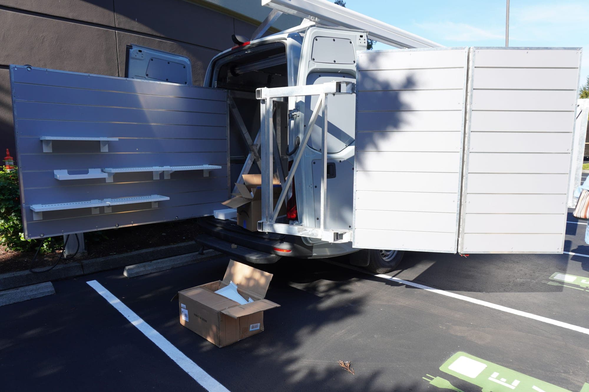 The van's side panels folded out flat, showing the empty slatwall shelving and adjustable brackets